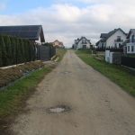 Dziurawa droga błonista pomiędzy budynkami.