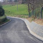 Droga z nowo położonym asfaltem. W tle skarpę podpartą płytami.