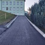 Asfaltowa droga. W tle widać czerwone serce na zakrętki oraz gmach szkoły.