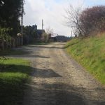 Droga żwirowa między polami i budynkami.