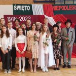 Grupa młodzieży przebrani w różne stroje [przedstawiają na sali gimnastyczną spektakl przed widownią.