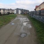 Dziurawa droga kamieniasta między budynkami.