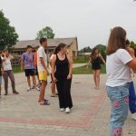 Grupa dzieci ubrana w krótkie stroje tańczy na kostce brukowej.