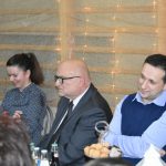 Dwóch mężczyzn i kobieta siedzą za stołem.