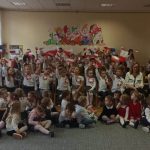 Duża grupa kilkudziesiąt dzieci ubrana w odiętne stroje, z flagami biało czerownymi pozują do zdjęcia.