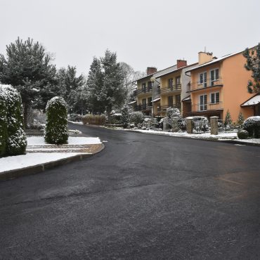 Ulica z nową nawierzchnią asfaltową, obok domki jednorodzinne.