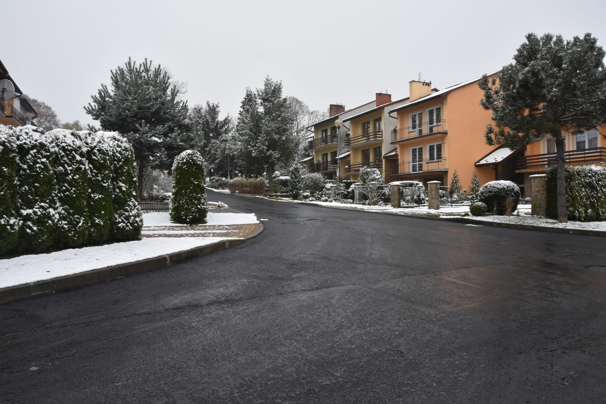 Ulica z nową nawierzchnią asfaltową, obok domki jednorodzinne.