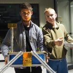 Dwóch chłopaków trzyma w rękach projekt techniczny.