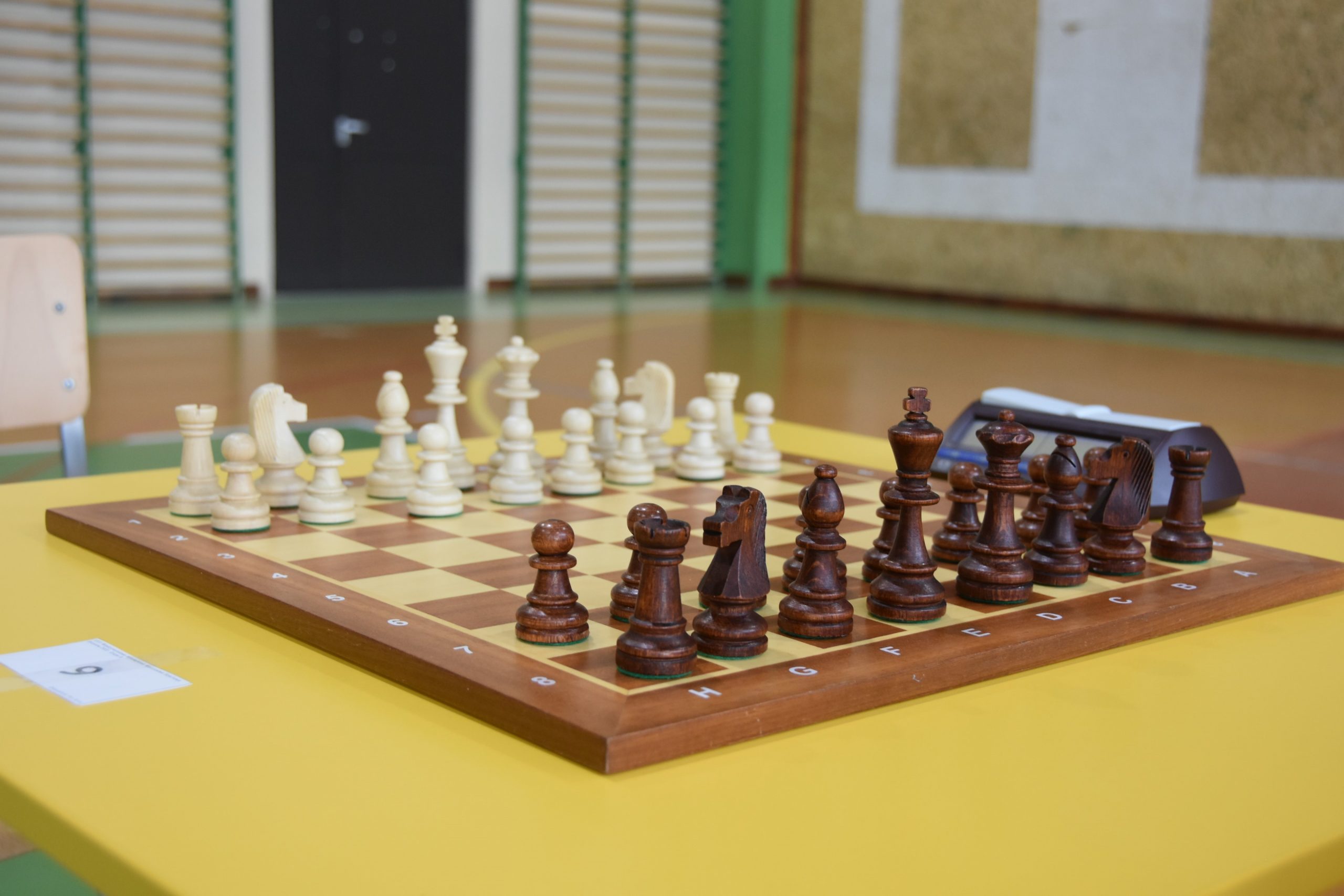 Szachownica z ułożonymi do gry szachami leząca na stole.