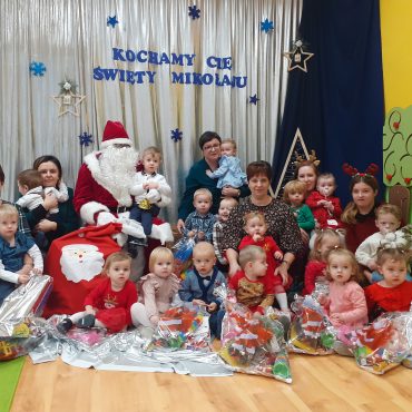Grupa dzieci pozuje do zdjęcia z Mikołajem.