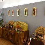 Szopki wielkanocne wyeksponowane w dużej sali. Na ścianie wiszą ikony aniołów.