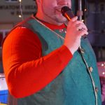 Dorosły mężczyzna w stroju elfa przemawiający za pomocą mikrofonu.