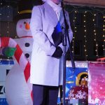 Dorosła kobieta w zimowym ciepłym stroju, przemawiająca ze sceny.