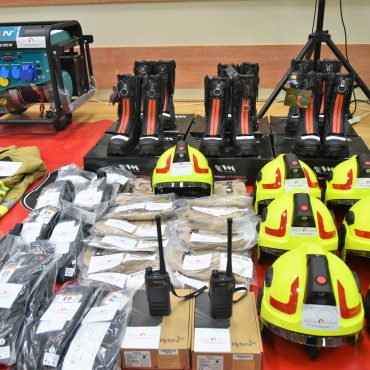 Nowy sprzęt strażacki rozłożony na rozległej sali.