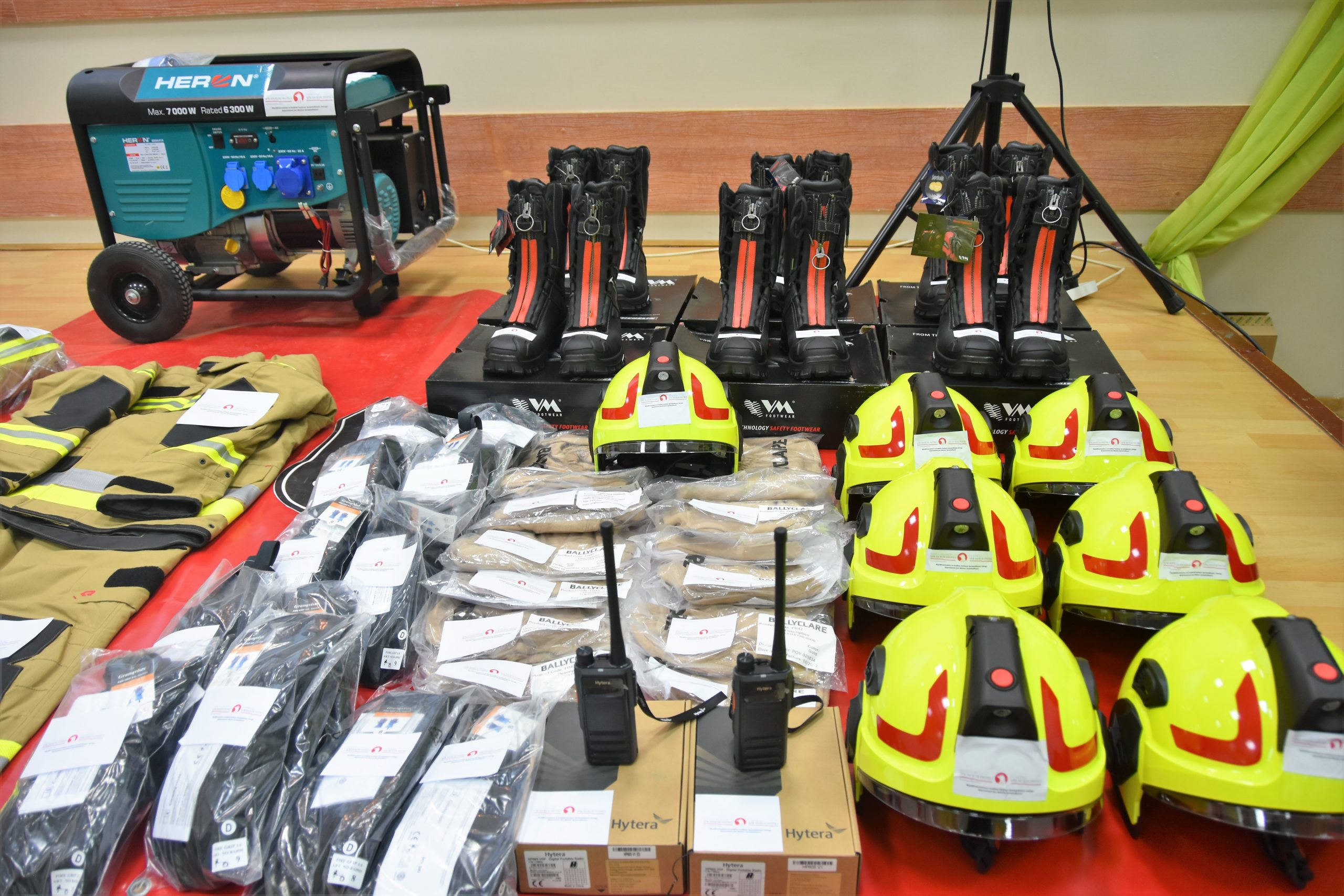 Nowy sprzęt strażacki rozłożony na rozległej sali.