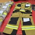 Nowe stroje strażackie rozłożone w pomieszczeniu
