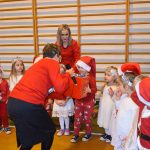 Dwie dorosłe kobiety i grupa dzieci. Jedno z dzieci trzyma prezent.