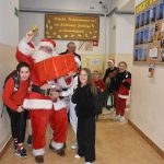 Grupa dziewczyn przytula się do mężczyzny przebranego w stroj mikołaja.