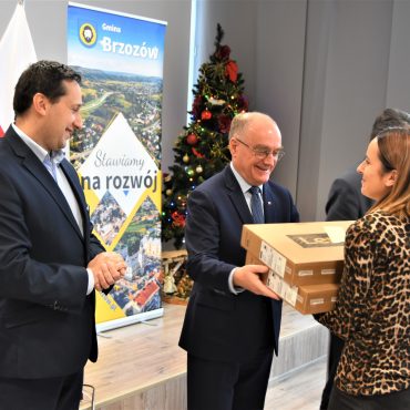 Trzech mężczyzn w garniturach wręczających upominki kobiecie.