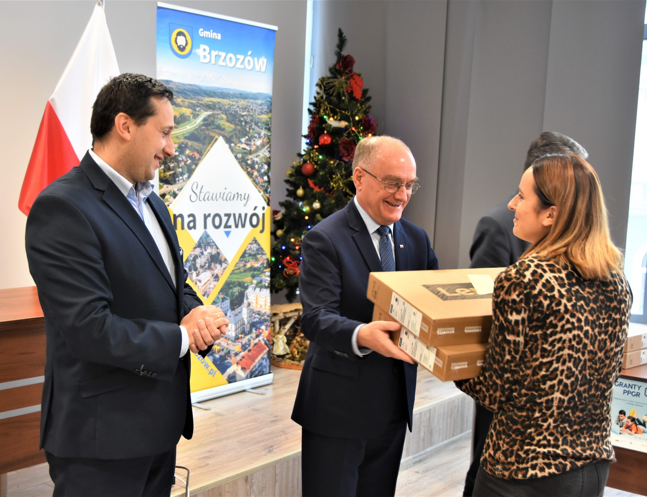 Trzech mężczyzn w garniturach wręczających upominki kobiecie.