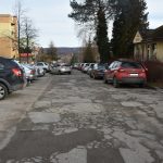 Droga asfaltowa zniszczona, dziurawa i popekana w centrum miasta między budynkami.