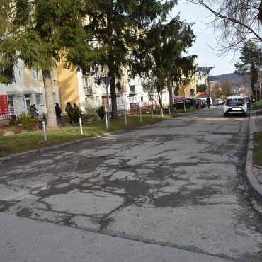 Droga asfaltowa zniszczona, dziurawa i popekana w centrum miasta między budynkami.