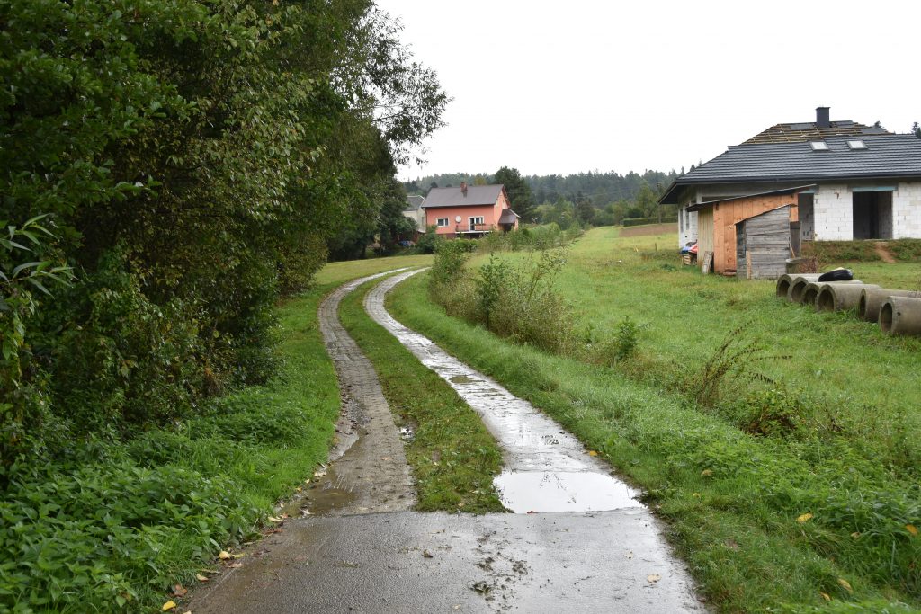 Droga kamienista między zabudową mieszkalną.