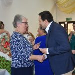 Młody mężczyna dzieli się opłatkiem ze starszą kobietą w niebieskiej bluzce.