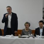 Młody mężczyzna w garniturze przemawia do zaebranych.