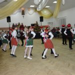 Grupa dzieci ubrana w stroje krakowskie tańczy krakowiaka.