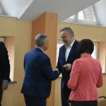 Mężczyzna w garniturze dzieli się opłatkiem z mężczyzną i kobietą.