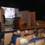 Grupa osób siedzi w fotelach w kinie i ogląda na projektorze film.