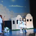 Kobieta i mężczyzna w strojach Józefa I Maryii oraz para dziewczynek w strojach aniołków na scenie.