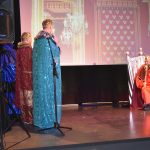 Czterech mężczyzn w stroju królów w przedstawieniu jasełkowym na scenie.