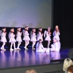 Grupa dzieci oraz kobieta w strojach aniołków wystepuje na scenie.