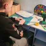 Chłopiec zajmuje się pracami technicznymi, siedząc przy biurku.