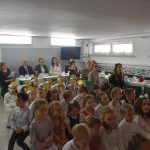 Grupa dzieci oraz dorosłych oglądających występ na salce.