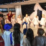 Grupa dzieci podczas wytępienia jasełkowego. Dzieci przebrane są w stroje świąteczne i stoją w kółku.