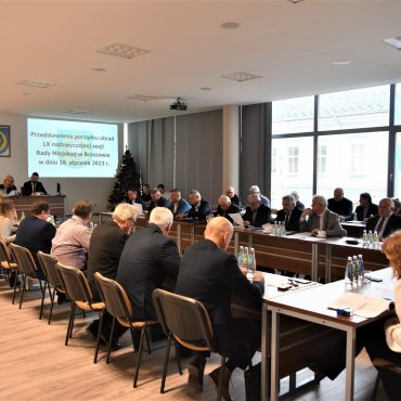 Grupa dorosłych osób różnej płci i wieku zasiadająca na dużej sali konferencyjnej.