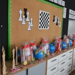 Nagrody i statułetki sportowe ułożone na półce.