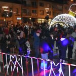 Grupa młodych osób tańczy przed sceną na rynku.