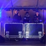 Trzech młodych mężczyzn na scenie zapuszcza muzykę.