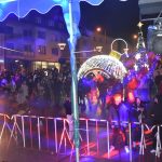 Grupa osób stoi przed budynkiem ratusza i słucha koncertu.