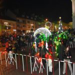 Grupa osób stoi przed budynkiem ratusza i słucha koncertu.