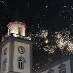 Nad wieżą ratuszą na ciemnym niebie rozbłyksują fajerwerki.