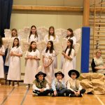 Grupa dzieci na sali gimnastycznej. Dziewczynki są ubrane w stroje aniołków a chłopcy w stroje góralskie.