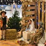 Cłopczyk w stroju rybaka przemawia do mikrofonu do dzieci ubranych w stroje Marii i Józefa.