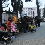 Grupa ludzi dzieci i dorosłych stoją pod kościołem. Na głowach mają barwne korony.