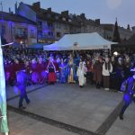 Grupa osób stoi na rynku podczas wydarzenia imprezowego.