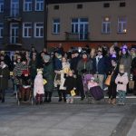 Grupa osób stoi na rynku podczas wydarzenia imprezowego.